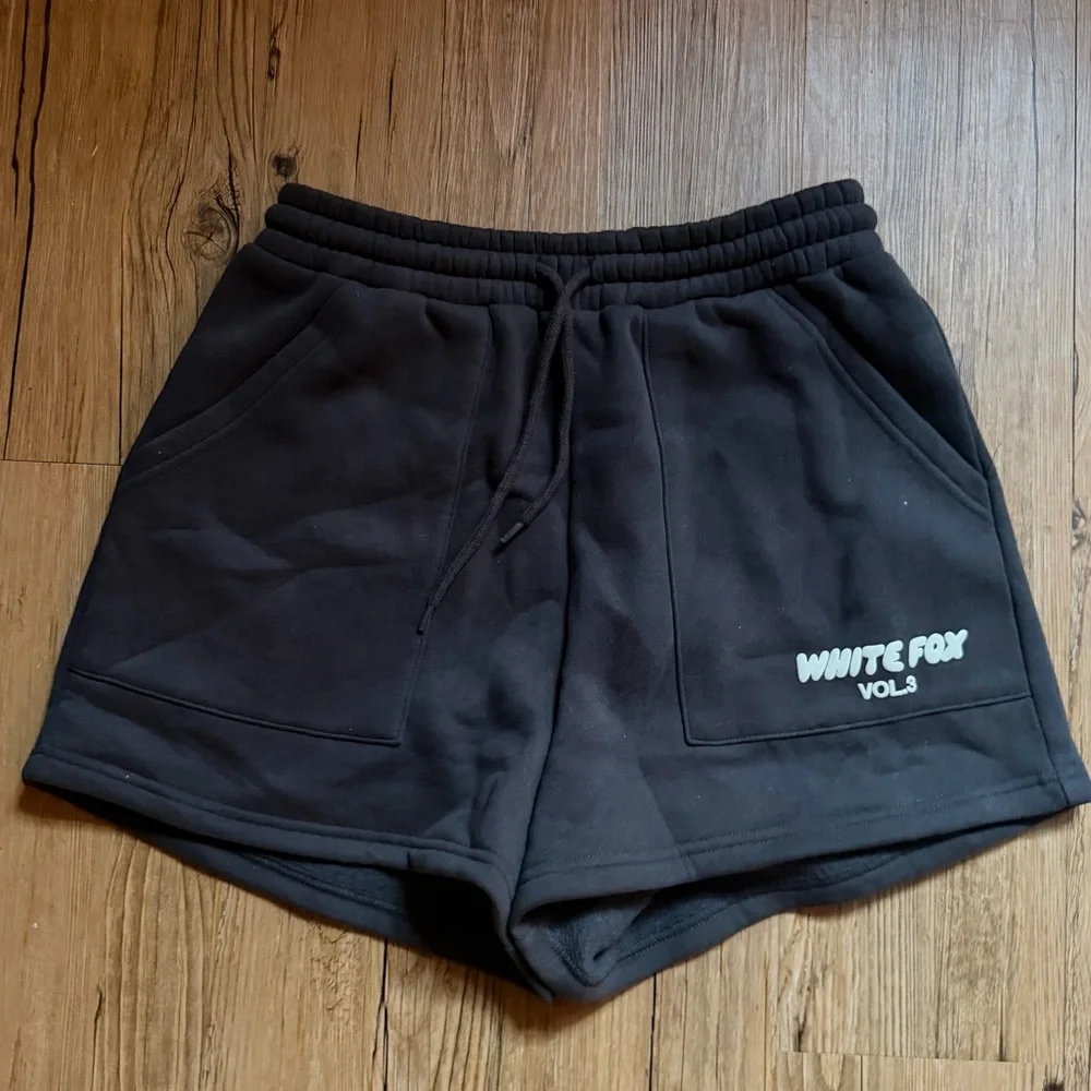White Fox Boutique charcoal shorts with white text reading 'WHITE FOX VOL.3'